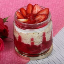 Glass jar filled with layers of strawberry cake, a delicious and portable dessert option for strawberry lovers.