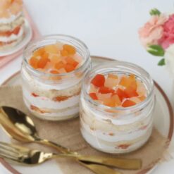 Pack of six glass jars filled with layers of fruit fiesta cake, bursting with a variety of fruity flavors.