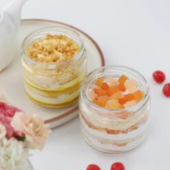 Glass jars filled with layers of butterscotch and mixed fruit cakes, a delicious combination for dessert lovers.