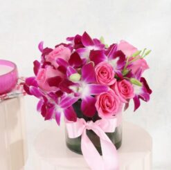 Orchids and pink roses in a circular vase - a harmonious floral arrangement for any occasion.