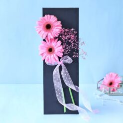 A slate container filled with a charming arrangement of sweet gerbera daisies, perfect for adding beauty to any space.