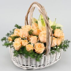 Handle basket arrangement featuring peach roses and white lilies, exuding elegance and charm for any occasion.