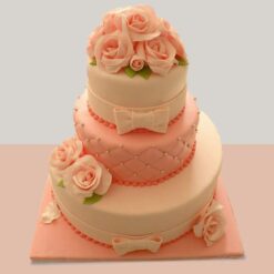 Elegant three-tier pink rose cake with intricate floral decorations, ideal for weddings and celebrations.